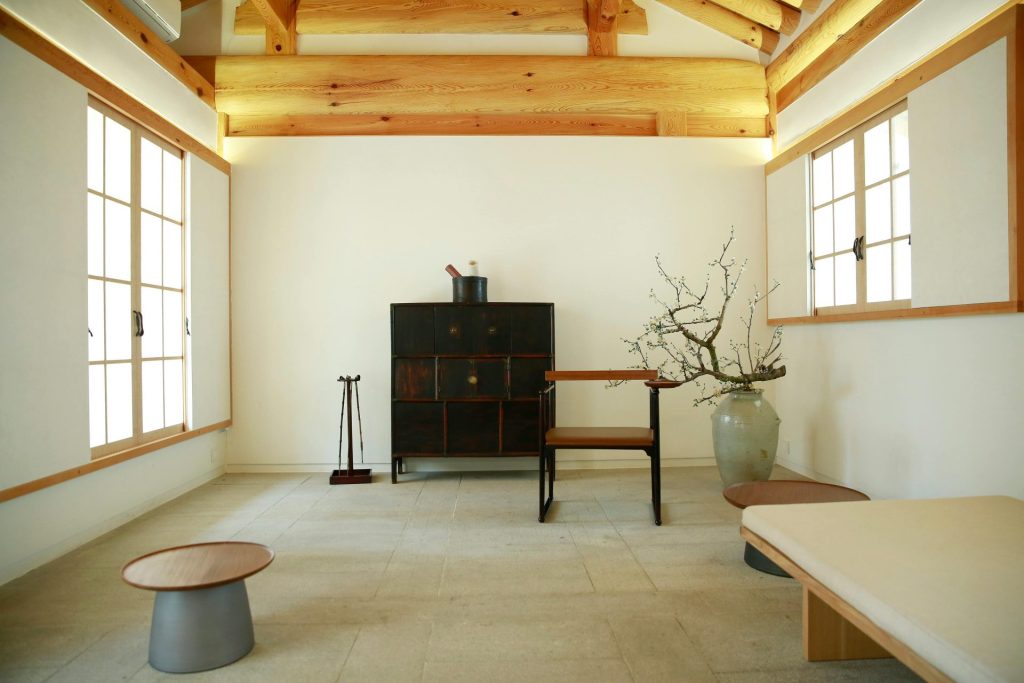 Une pièce sereine d'inspiration japonaise, dotée d'un mobilier minimaliste et de poutres en bois naturel.