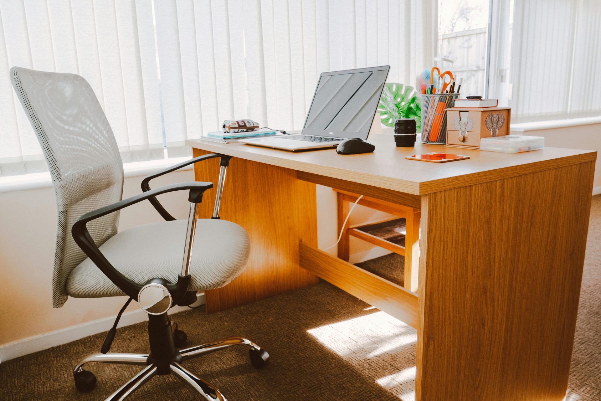 Un espace de travail moderne comprenant un bureau en bois, une chaise, un ordinateur portable et une lumière naturelle vive.